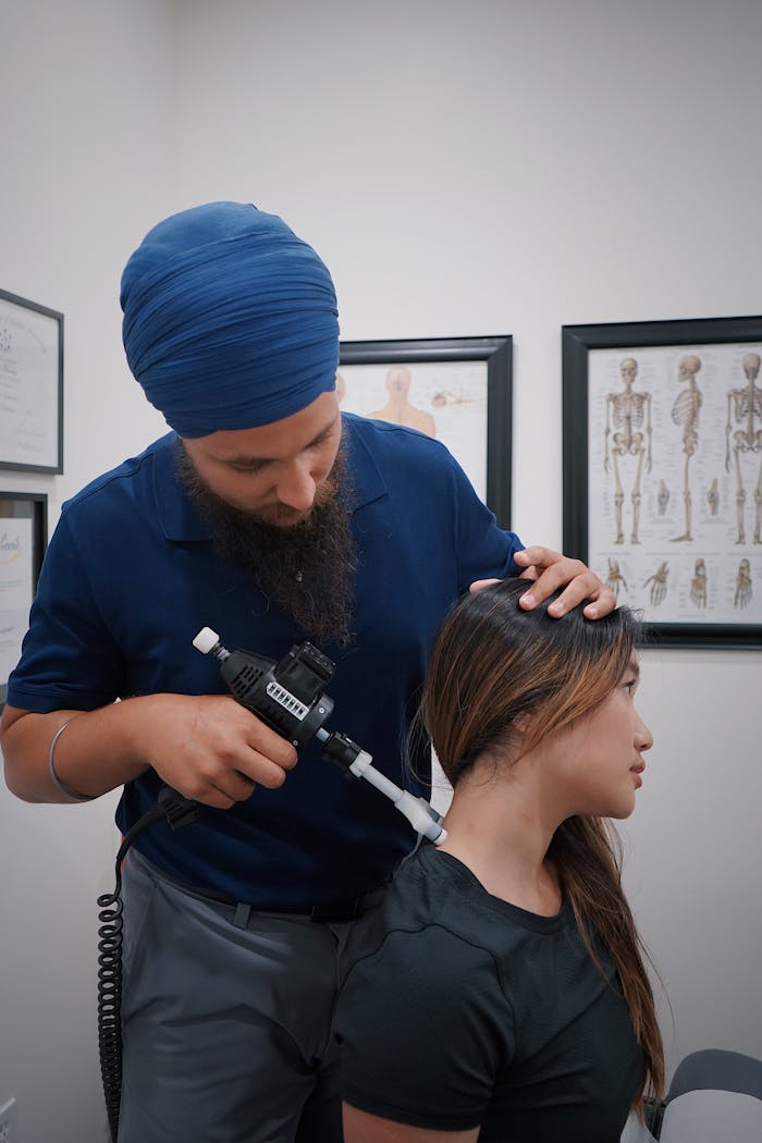 Chiropractor performing neck adjustment on woman in a clinical setting with anatomical charts.