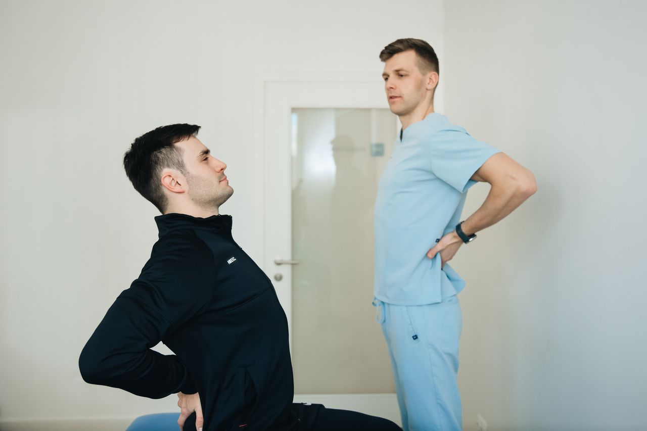 services-03 A physiotherapist instructs a patient on back exercises in a clinic setting.